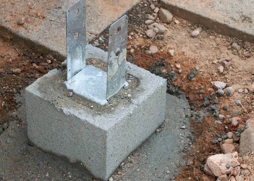 Galvanized post base bracket set into a concrete pier footing