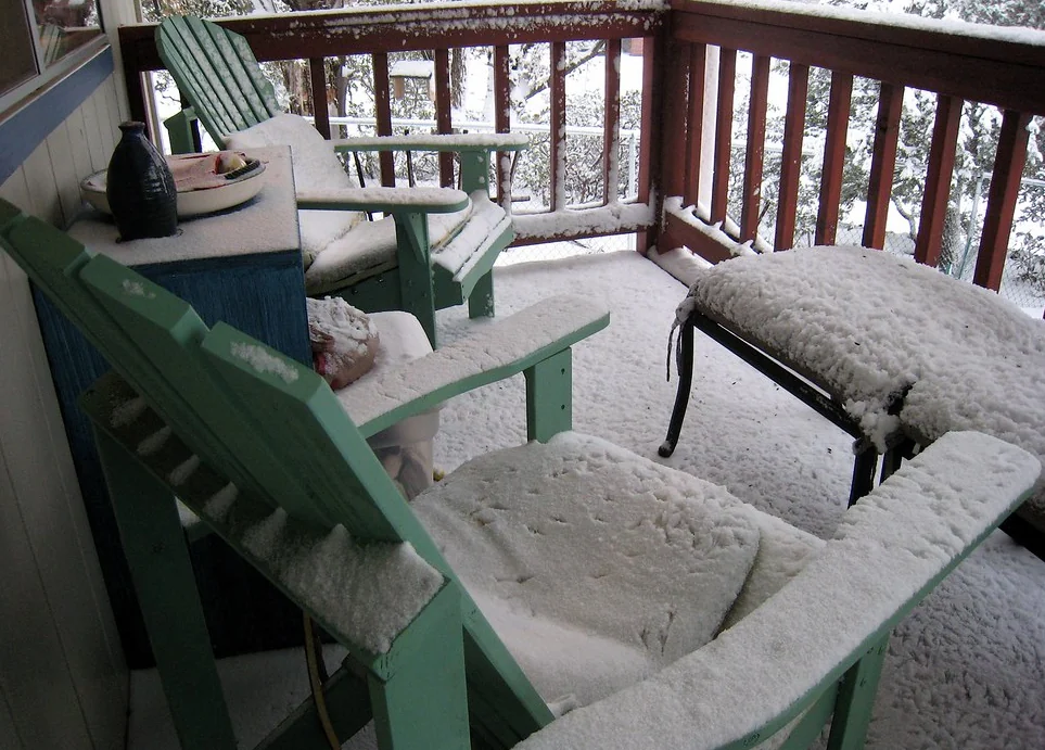 Snow-covered chairs on a timber deck